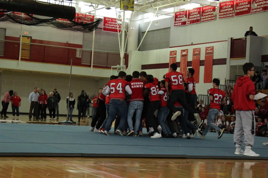 The football team runs out to the center of the gym when they are announced