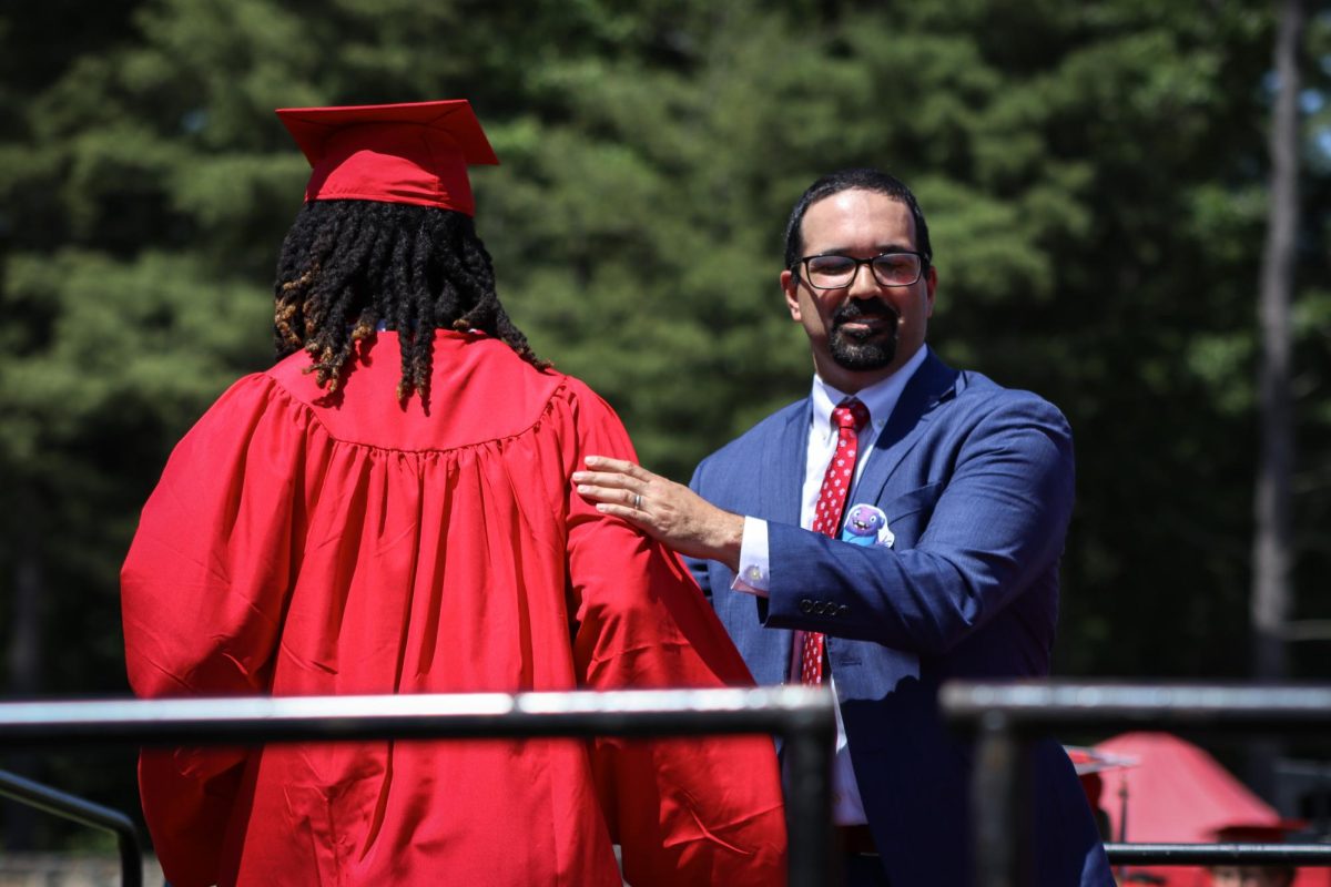 Principal Medeiros claps Aaron Horton on the back after receiving his diploma |by Ella Spuria