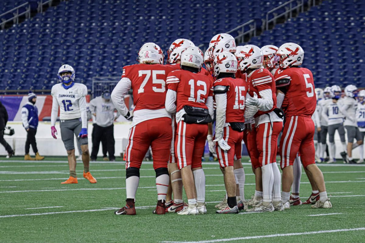 The team huddles on the offensive line before the play |by Ella Spuria