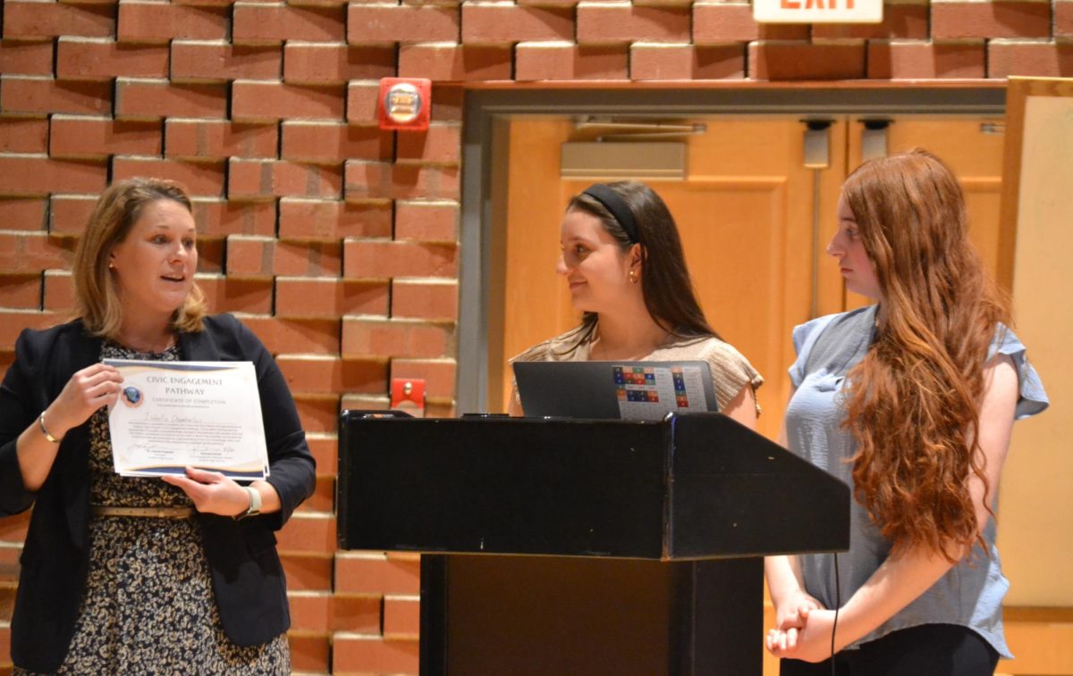History teacher and CEP Director Pamela Porter present Lillyanna Resendes and Isabella Chamberlain with their Civic Engagement Pathway seal | by Jacqueline Browning